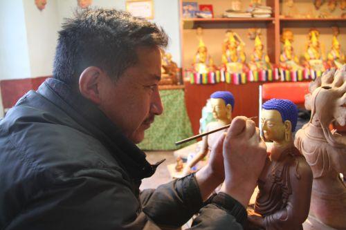 邊巴在對泥塑佛像上色。
